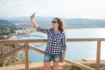 Travel, vacation and holiday concept - Young woman having fun, taking selfie, crazy emotional face and laughing.