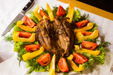 Fried chicken with yellow pepper red tomato on a plate with greens.
