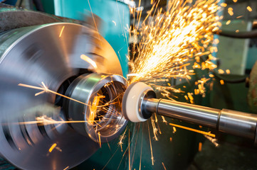 End processing of a metal surface with an abrasive stone on a circular grinding machine, sparks fly...