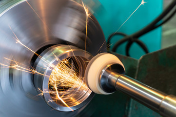 End processing of a metal surface with an abrasive stone on a circular grinding machine, sparks fly in different directions.