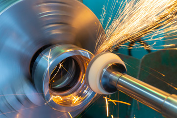 End processing of a metal surface with an abrasive stone on a circular grinding machine, sparks fly in different directions.