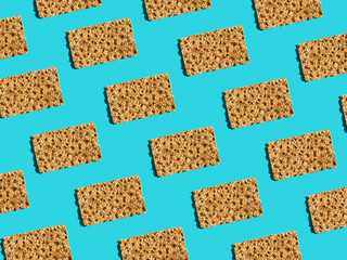 Pattern from scandinavian rye whole grain crispbreads with sesame seeds on solid blue background. Harsh shadows hard light. Trendy minimalist pop art style. Creative food art poster. Fiber slow carbs
