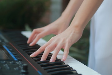 Closeup of teenage girl hands playing music with electronic keyboard.