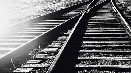 A railway track litted by the sunb black and white.