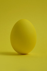 One yellow painted Easter egg stand on a yellow background.