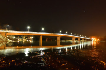 Fototapeta na wymiar Oświetlony most w ciemną, gwiaździstą noc