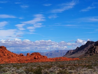 View of red rock and mountains with sky and clouds in valley of fire