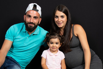 pregnant mother with her family sit on floor black background