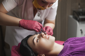 Cosmetologist making an ingection to her client. Woman beauty procedure, lip augmentation...