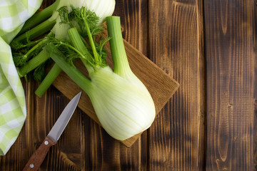 Fennel on the cutting board on the brown wooden background.Top view.Copy space.