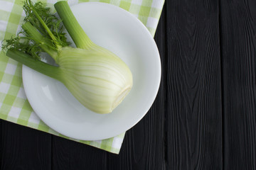 Fennel in the white plate on the black wooden background.Top view.Copy space.