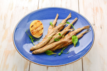 wooden board with smelt fried fish and salad