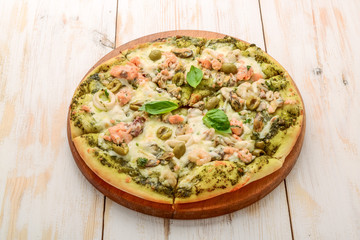Pizza with shrimp, salmon and olives, pesto