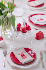 Happy easter. Decor and table setting of the Easter table is a vase with white tulips and dishes of red and white color. Easter colored eggs with white polka dots.