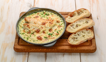 White fish casserole with cheese, sour cream and onion on a wooden table