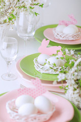 Happy easter. Decor and table setting of the Easter table is a vase with pink tulips and dishes of pink and green color.