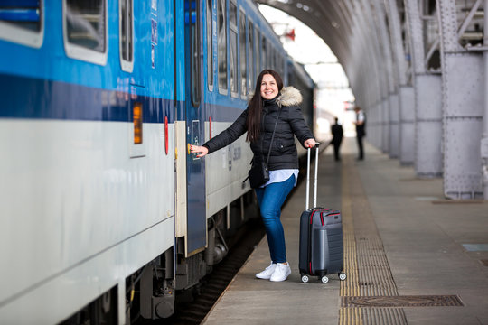 Pretty young woman with luggage waiting at the traint station for her train, transportation concept