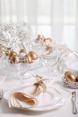 Happy Easter! Golden decor and table setting of the Easter table with white dishes of white color.