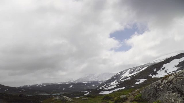 Mountain panorama from the Gamle Strynefjellsvegen Riksvei 258 in Oppland and Sogn og Fjordane, Norway, with snow and ice covered mountains, the glacier lake Langvatnet and a cloudy sky.