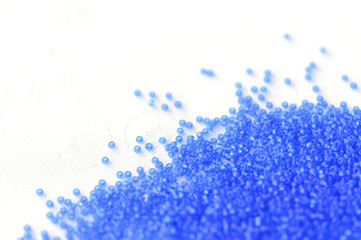 Transparent seed beads dark blue color on a textile background close up
