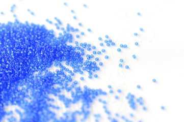 Transparent seed beads dark blue color on a textile background close up