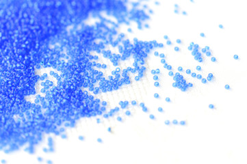 Transparent seed beads dark blue color on a textile background close up