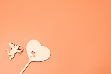 on a pink, beige background heart carved from wood, which shoots an angel
