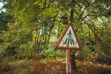 Old rusty, frayed, scratched red triangular traffic sign - pedestrian crossing in radioactive zone in Pripyat city. Chornobyl exclusion zone