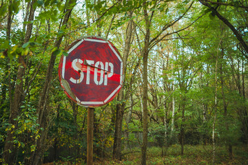 Stop sign - old rusty, frayed, scratched red road sign in radioactive zone in Pripyat city....