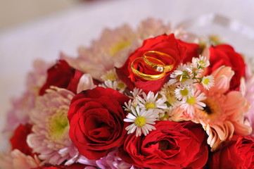 wedding ring in box on red flowers