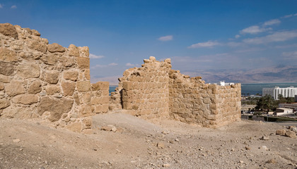a section of a partially reconstructed ancient roman fortress sits above the dead sea resort town of ein bokek with the moav mountains of jordan in the background