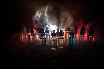 Vape concept. Smoke clouds and vape liquid bottles on dark background. Light effects. Useful as...