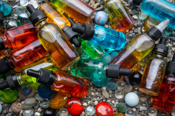 Vape concept. Beautiful colorful vape liquid glass bottles outdoor on stones. Useful as background...