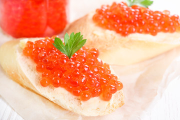 Snacks with red caviar on white paper close-up
