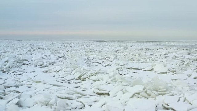 Close up of snow-covered ice shoves in arctic cold waters. Peacefully flying over frozen lake.