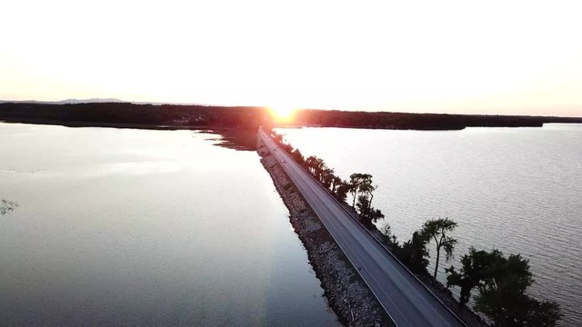 Cars traveling over lake champlain causeway at sunset