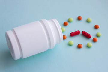 Multicolored pills from white jars on a blue background