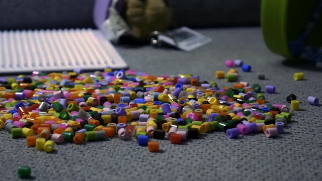 Child making art with perler beads,on the sofa.