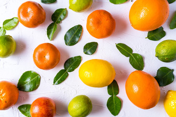 Flat lay the raw fresh citrus fruit - orange, lemon, lime and tangerine with lime leaves.