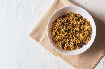 Organic granola in a bowl , on napkin, over white background , flat lay.