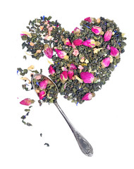 Floral dry tea in the form of heart. green tea with flowers and fruit pieces in a spoon on a white. blend tea
