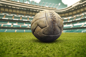 Vintage football ball on the grass field in stadium