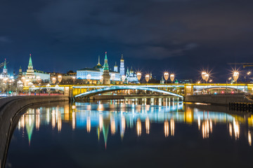 Obraz premium Illuminated Moscow Kremlin and Bolshoy Kamenny Bridge in the rays of setting sun. View from the Patriarshy pedestrian Bridge in Russia. Evening urban landscape in the blue hour