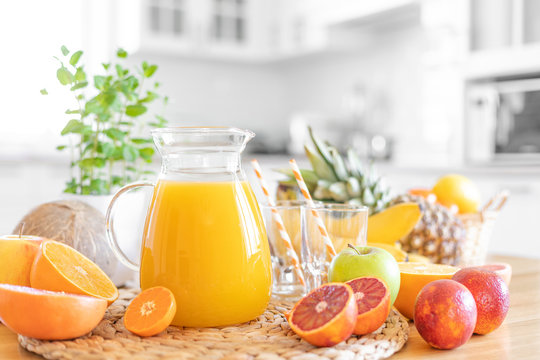 Multifruit juice and fresh fruit on table on kitchen background closeup