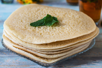 close up of Moroccan pancakes Baghrir or crapes with 1000 holes served with honey, tea with nana ,...