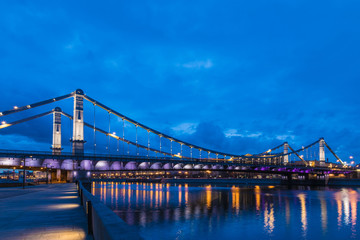 Naklejka na ściany i meble Krymsky Bridge or Crimean Bridge across the Moskva river in Moscow in the rays of setting sun in the evening blue hour with illumination