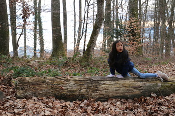Jeune fille enfant asiatique posant sur un tronc d'arbre avec malice