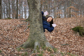 Jeune fille enfant asiatique cachée derrière un arbre faisant coucou