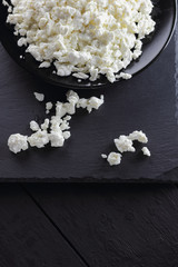 Cottage cheese on black slate board. Cheese on black plate. Soft cheese for diet on black boards. Healthy dairy product for breakfast. Concept