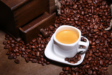 Fresh roasted coffee beans in burlap sack, espresso in cup and grinder on stone background.